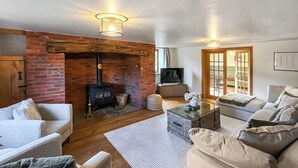 A living room with a brick fireplace, a television, and a sofa. - 5 bedroom accommodation in St. Asaph (St. Asaph)