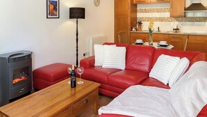 Un salon chaleureux avec un canapé rouge, une table basse en bois et une cheminée.
