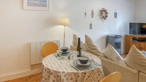 A dining area with a round table, chairs, a lamp, and a bottle of wine. - Atlantic Cottage - UK48935 (Crowlas, near Penzance)