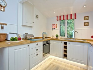 A kitchen with white cabinets, a wooden countertop, a toaster, a sink, and a window with a view of greenery. - Tuckenhay, Millers Thumb - HHV (Bow Creek, between Dartmouth and Totnes)