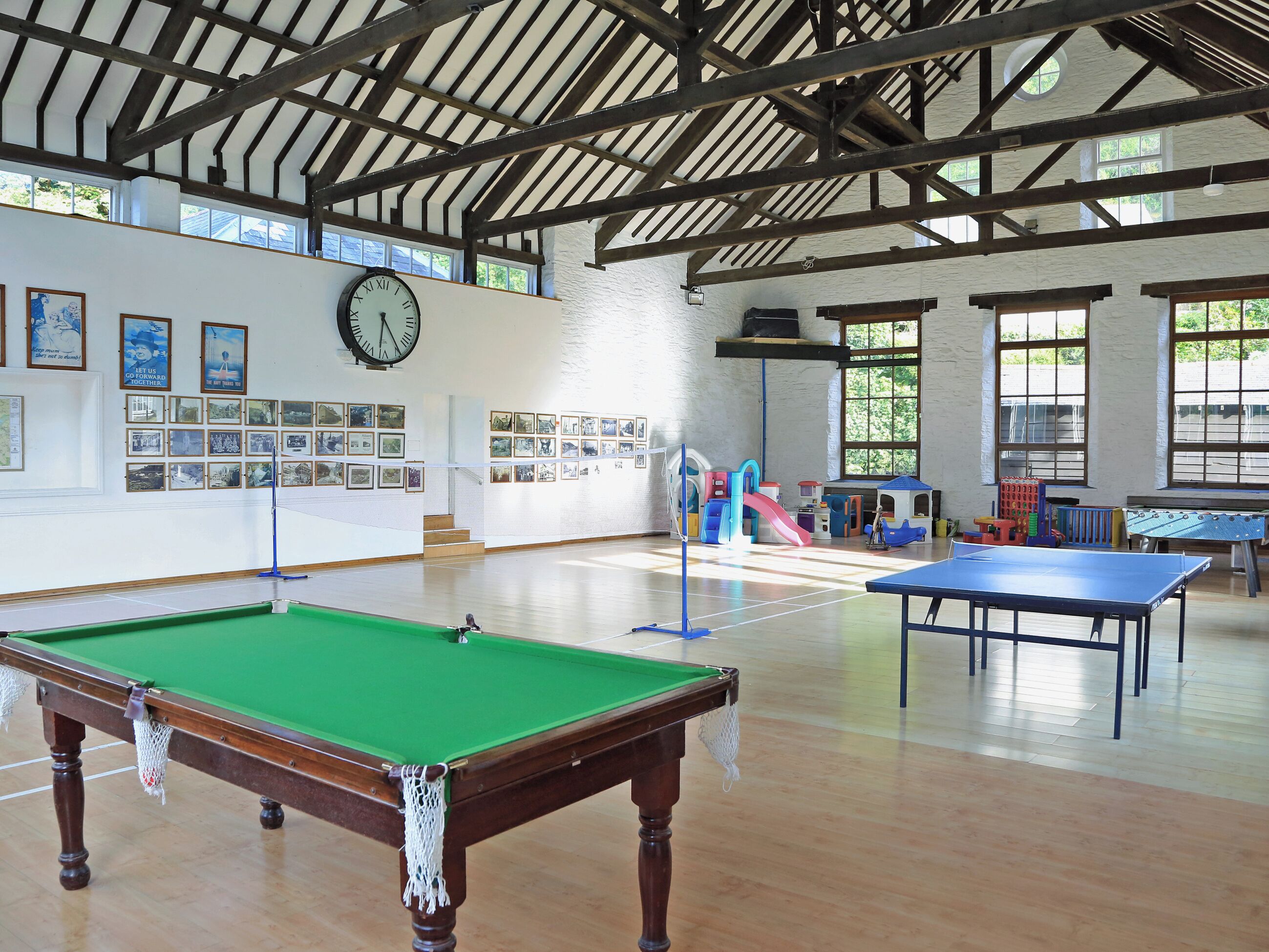 Un grand espace intérieur comprenant une table de billard, une table de jeu de flipper et du matériel de jeux pour enfants.
