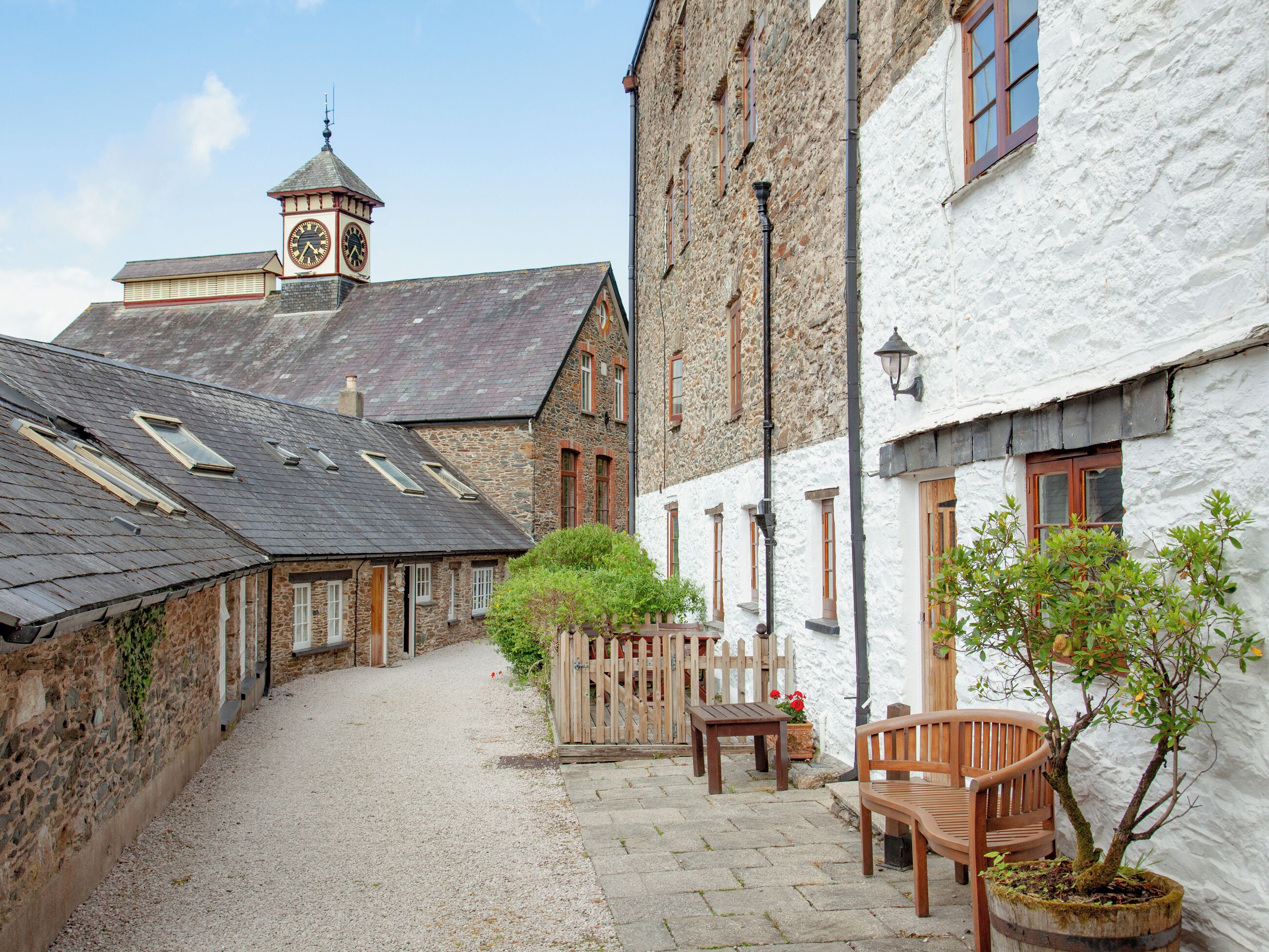 A narrow cobblestone alley with stone buildings, a wooden fence, and a bench.