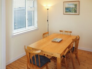 A dining area with a wooden table and chairs, a window with blinds, a floor lamp, and a framed picture on the wall. - 3 bedroom accommodation in Lower Largo (Lower Largo)