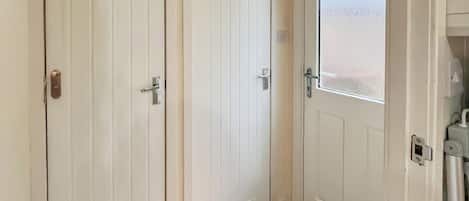 Un conjunto de puertas blancas con un picaporte metálico, una puerta de cristal y un felpudo.