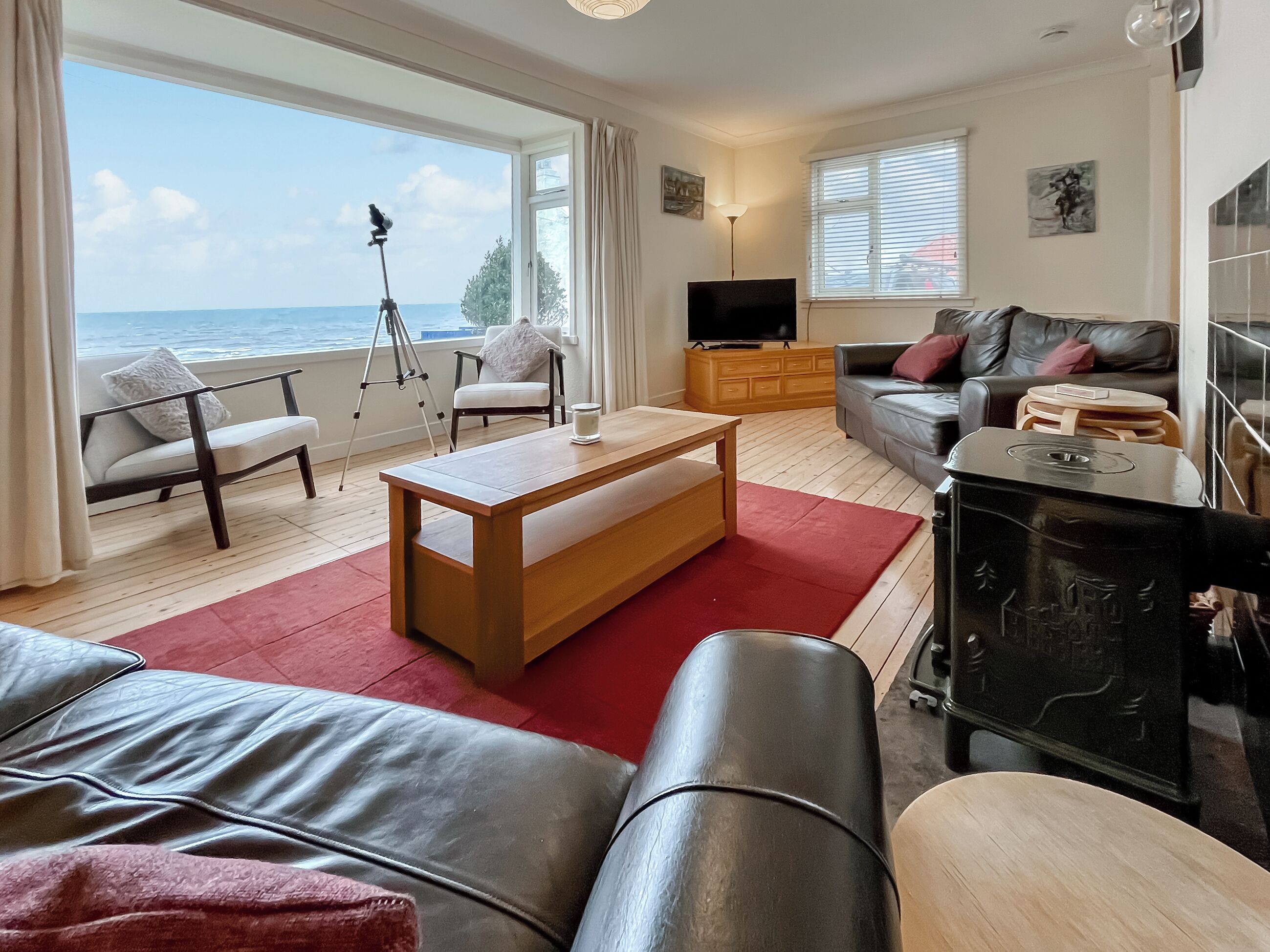Un salon comprenant un canapé, une table basse, un téléviseur et un balcon équipé d’un trépied.