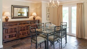 A dining area with a glass table, metal chairs, a wooden cabinet, and a chandelier. - 3 bedroom accommodation in Bettiscombe, near Lyme Regis (Bettiscombe, near Lyme Regis)