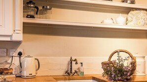 A kitchen with a wooden countertop, a sink, a kettle, a basket of flowers, and a toaster. - 3 bedroom accommodation in Bettiscombe, near Lyme Regis (Bettiscombe, near Lyme Regis)