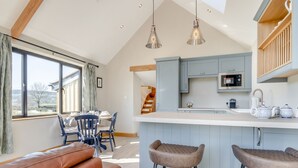A modern kitchen with a large island, bar stools, and a dining area with a view. - 1 bedroom accommodation in Mold and the Clwydian Range (Mold and the Clwydian Range)