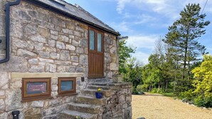 A stone building with a wooden staircase leading to a door, surrounded by gravel and greenery. - 1 bedroom accommodation in Mold and the Clwydian Range (Mold and the Clwydian Range)