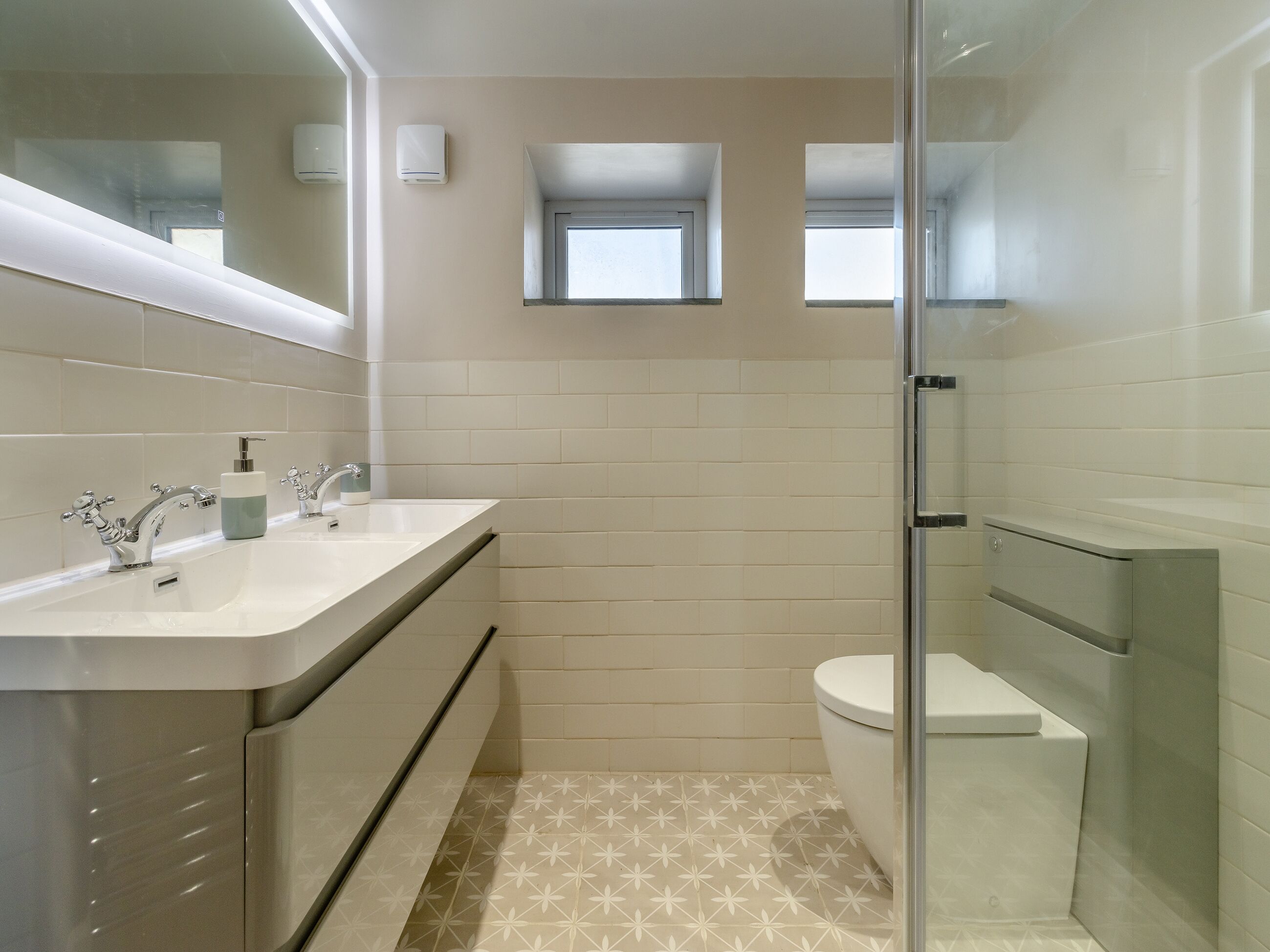 Un baño moderno con lavamanos doble, inodoro y cabina de ducha.