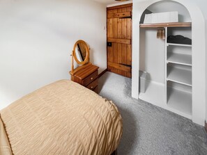 A bedroom with a bed, a wooden dresser with a mirror, a wardrobe, and a built-in shelving unit. - 10 The Apostles - UK37312 (Lochranza)