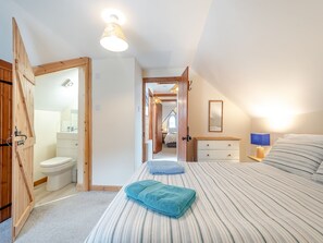 A bedroom with a bed, a bedside table with a lamp, a mirror, and a bathroom with a toilet and sink. - 10 The Apostles - UK37312 (Lochranza)