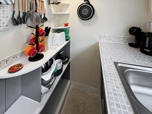A kitchen with a white countertop, a sink, and various kitchen utensils and appliances. - Back Row Bothy - UK37313 (Lochranza)