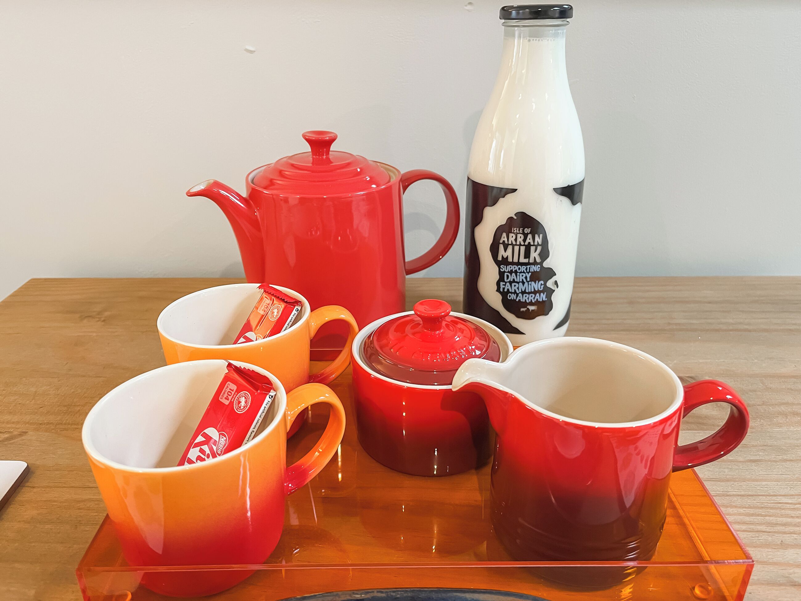 A table with a teapot, milk bottle, and cups.