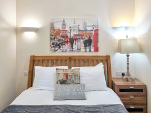 A hotel room with a bed, a nightstand, a lamp, and a wall painting of a city scene. - Westfield Courtyard - UK50704 (Fitling, near Burton Pidsea)