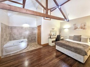 A bedroom with a large bed, a desk, a chair, a vanity, and a bathtub. - Westfield Courtyard - UK50704 (Fitling, near Burton Pidsea)
