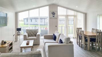 Amplia sala de estar con un ventanal grande, comedor con mesa y sillas de madera, y un conjunto de sofás.