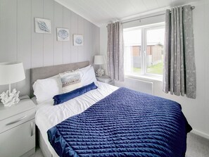 A neatly arranged bedroom with a bed, bedside tables, and a window with curtains. - 3 bedroom accommodation in Fitling, near Burton Pidsea (Fitling, near Burton Pidsea)