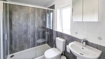 Un baño moderno con ducha envuelta en vidrio, inodoro y lavamanos.