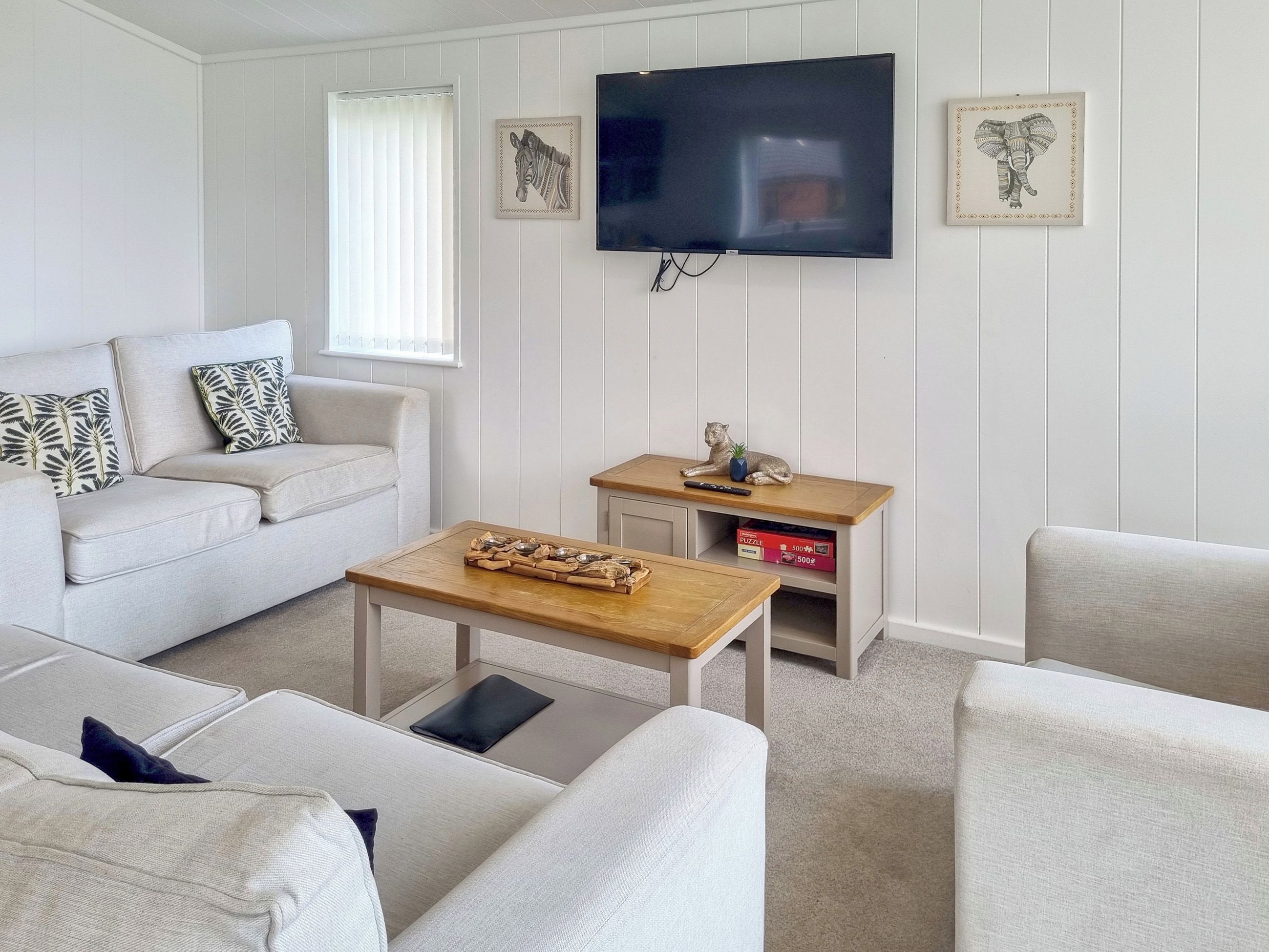 A modern living room with a flat-screen TV, a sofa, a coffee table, and a small side table with a statue.