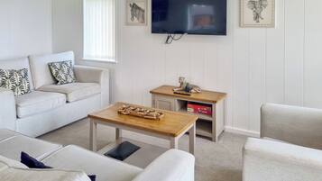 A modern living room with a flat-screen TV, a sofa, a coffee table, and a small side table with a statue.
