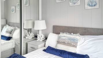 Una habitación de hotel con cama, mesitas de noche, lámparas y cuadros en la pared.