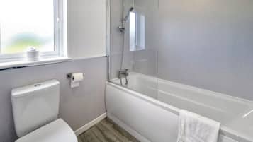 A modern bathroom with a toilet, a shower with a glass door, and a bathtub.