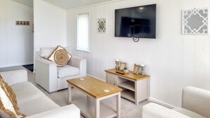 A living room with a sofa, a coffee table, a TV mounted on the wall, and decorative items on a side table. - Cherry Blossom 37 - UK50706 (Fitling, near Burton Pidsea)