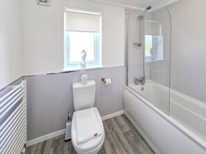 Une salle de bain équipée de toilettes, d’une fenêtre, d’une douche et d’un radiateur.