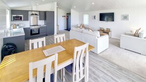 Uma cozinha moderna com área de jantar, uma sala de estar com sofá e televisão na parede.