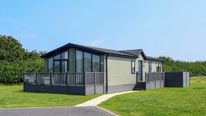 Ein modernes Einfamilienhaus mit großen Fenstern, einer überdachten Veranda und einem gepflegten Rasen.