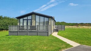 Ein modernes eingeschossiges Haus mit Balkon, gepflasterter Auffahrt und Rasengarten.