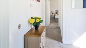 A hallway with a wooden cabinet, a potted plant, and a painting of a bridge. - Cherry Blossom 43 - UK50711 (Fitling, near Burton Pidsea)