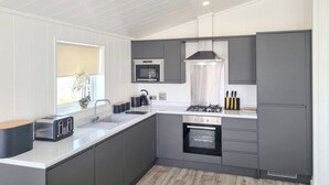 A modern kitchen with grey cabinets, a stainless steel range hood, a microwave, and a built-in oven.