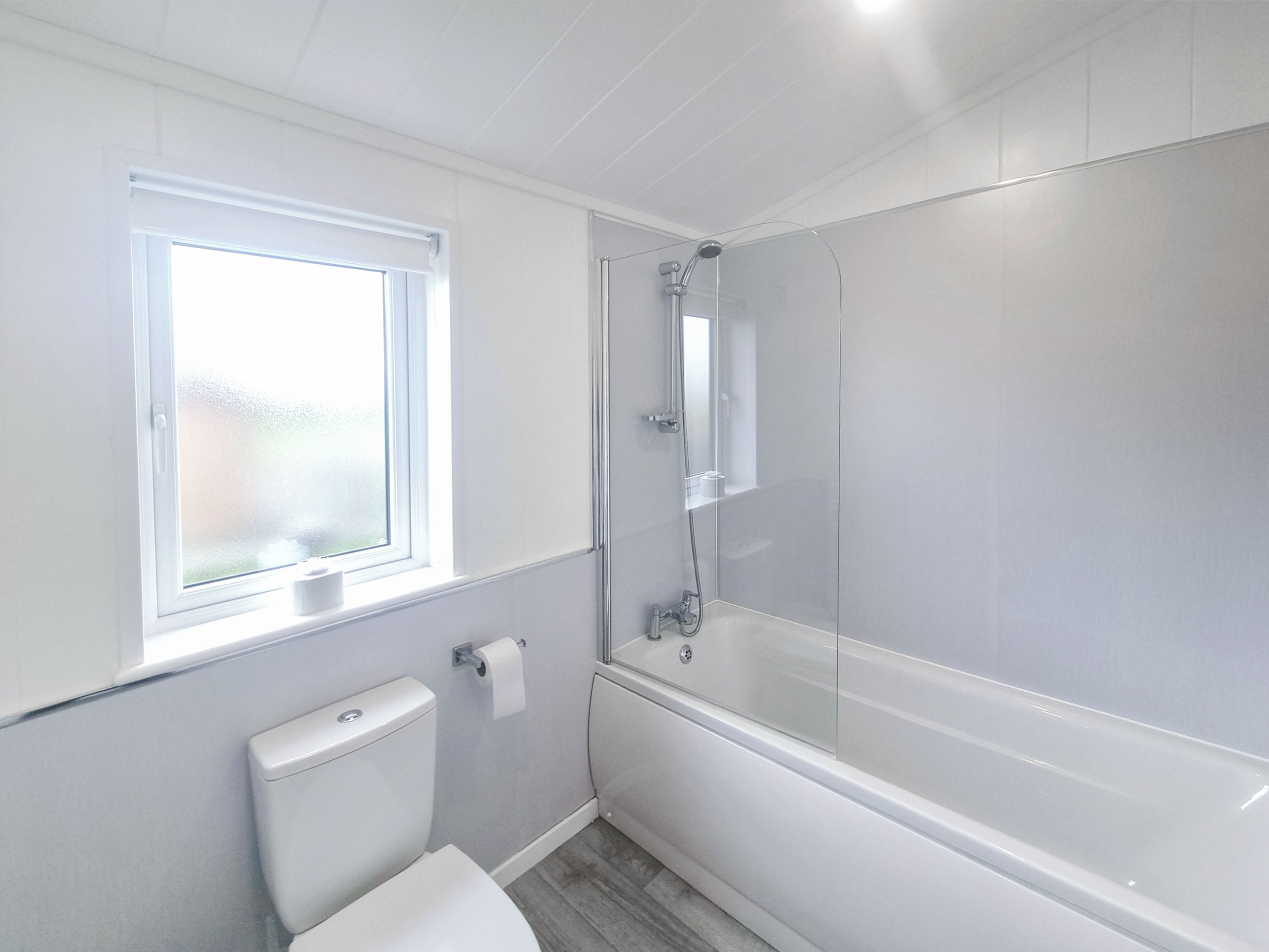 A bathroom with a toilet, a shower, and a window.