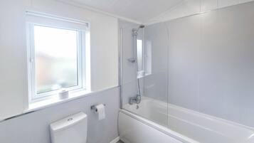 A bathroom with a toilet, a shower, and a window.