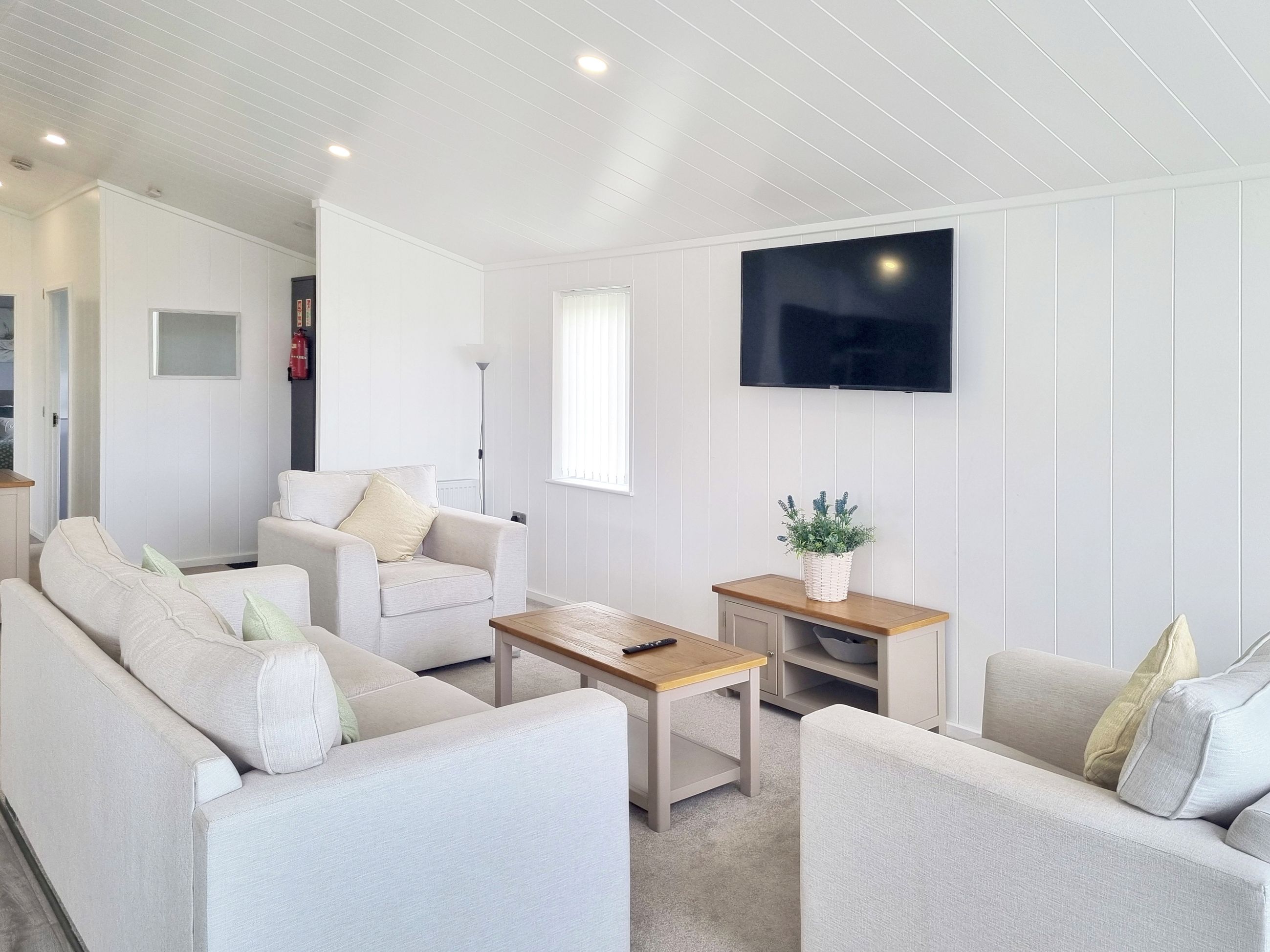 A modern living room with a sofa set, a coffee table, and a TV mounted on the wall.