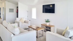 A modern living room with a sofa set, a coffee table, and a TV mounted on the wall.