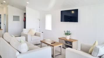 A modern living room with a sofa set, a coffee table, and a TV mounted on the wall.