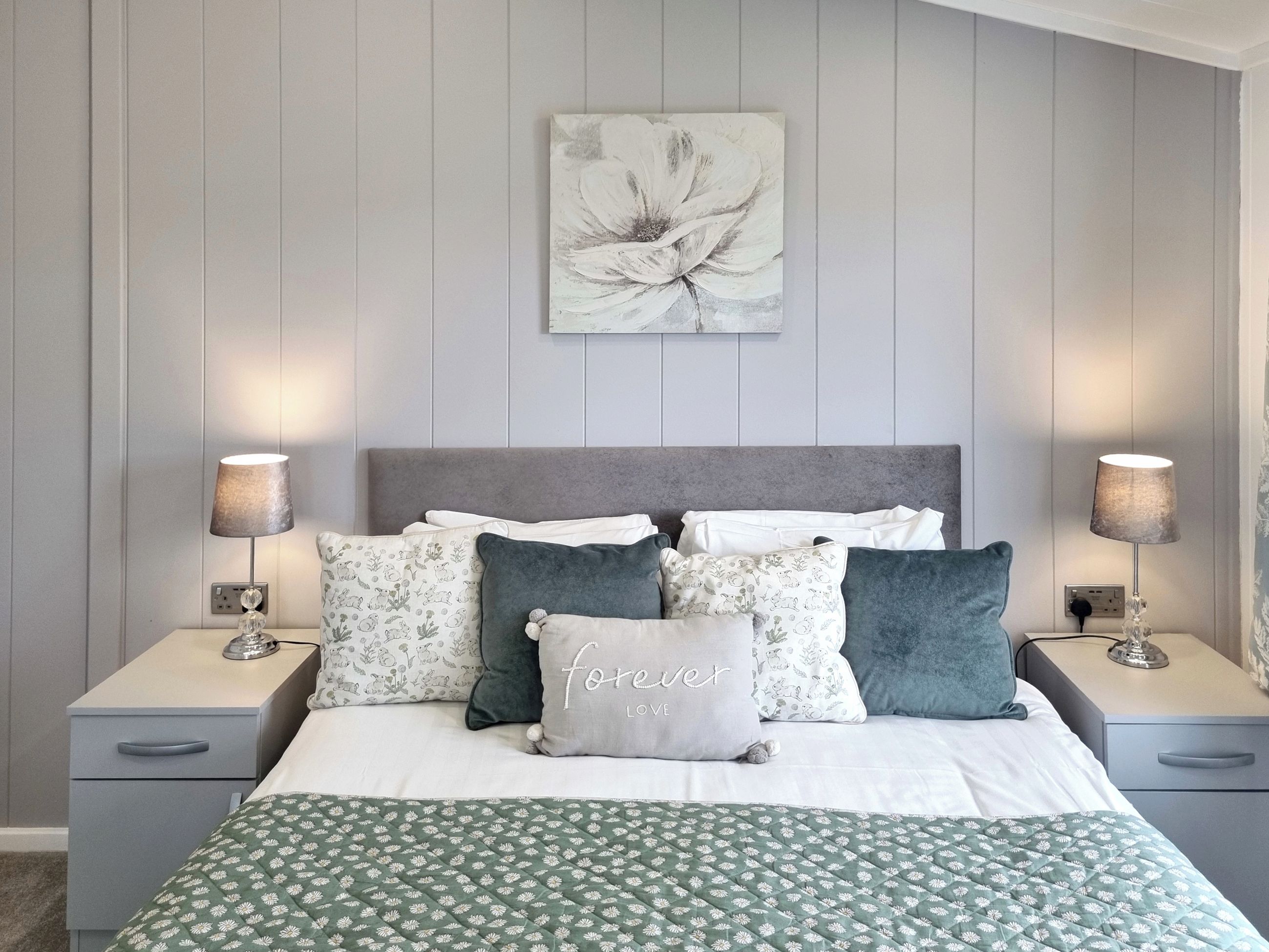 Una camera da letto con un letto, due comodini, una lampada e un’opera d’arte appesa al muro.