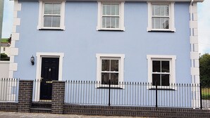 Ein zweistöckiges Gebäude mit hellblauer Fassade, weißen Fensterrahmen und einer schwarzen Tür.