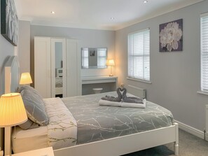 A bedroom with a bed, bedside lamps, a dresser, a mirror, and a window with blinds. - 3 bedroom accommodation in Llanon, near Aberaeron (Llanon, near Aberaeron)