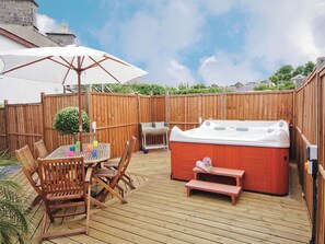 A wooden deck with a hot tub, a table with chairs, and a patio umbrella. - 3 bedroom accommodation in Llanon, near Aberaeron (Llanon, near Aberaeron)