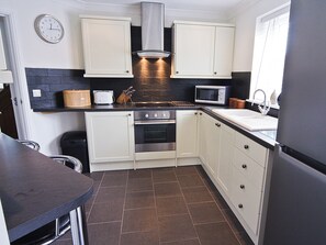 A kitchen with white cabinets, a microwave, a stove, and a sink. - 3 bedroom accommodation in Llanon, near Aberaeron (Llanon, near Aberaeron)