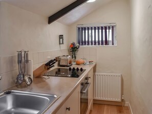 A compact kitchen with a sink, stove, toaster, and a window with curtains. - 2 bedroom accommodation in Liskeard (Liskeard)