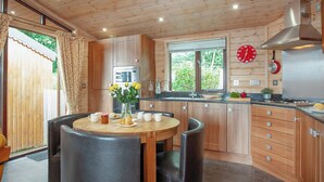 A modern kitchen with wooden cabinets, a stainless steel range hood, and a dining area with a table and chairs. - 2 bedroom accommodation in Harpford, near Sidmouth (Harpford, near Sidmouth)