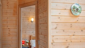 A wooden cabin interior with a cozy bed, a nightstand, and a wall-mounted light fixture. - 2 bedroom accommodation in Harpford, near Sidmouth (Harpford, near Sidmouth)