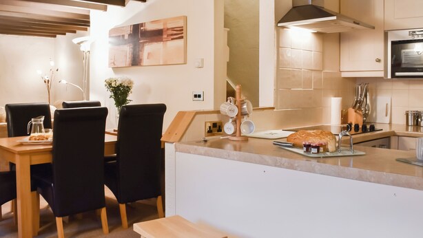 Eine moderne Küche mit einer zentralen Kochinsel, schwarzen Stühlen und einem Esstisch.