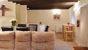 Ein gemütliches Wohnzimmer mit einer Couch, einem Couchtisch und einem Essbereich mit Stühlen und einem kleinen Tisch.