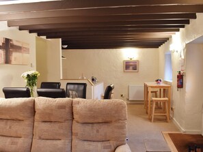 Ein gemütliches Wohnzimmer mit einer Couch, einem Couchtisch und einem Essbereich mit Stühlen und einem kleinen Tisch.